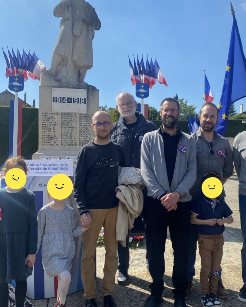 4 adultes et 3 enfants devant le monument aux morts de la guerre